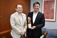 太宰府市長と奈良市長が二人そろって笑顔の様子。奈良市長は手元に太宰府市のお酒である東風の梅の瓶を持っています。